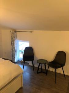 um quarto com 2 cadeiras, uma mesa e uma cama em B&B Emma em Geleen