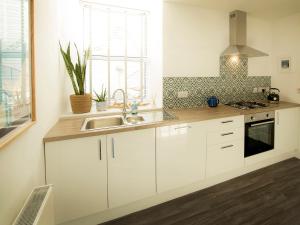 a kitchen with white cabinets and a sink at Sandpiper Cottage in Buckie