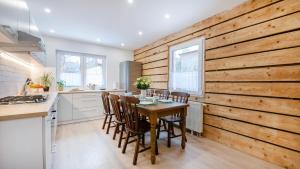 a kitchen with a wooden wall with a table and chairs at Domek pod Kogutem in Szklarska Poręba