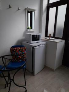uma cozinha com um micro-ondas, uma cadeira e uma janela em Casa das Netas em Lagos