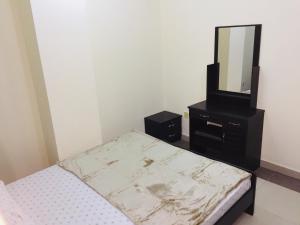 a bedroom with a bed and a dresser with a mirror at FURNISHED BEDROOM APARTMENT IN NAZIR PLAZA in Ajman 