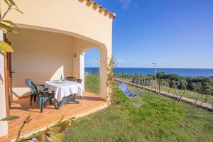 a patio with a table and chairs and the ocean at residence baia sant anna con piscina in Tanaunella
