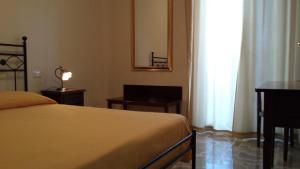 a bedroom with a bed and a desk and a window at B&B Capo Sant'Alessio in SantʼAlessio Siculo