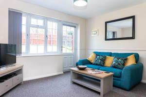 a living room with a blue couch and a mirror at Modern 2 Bedroom House, Sleeps 5 with Parking and Garden in Gloucester