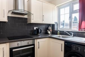 a kitchen with white cabinets and a sink at Modern 2 Bedroom House, Sleeps 5 with Parking and Garden in Gloucester