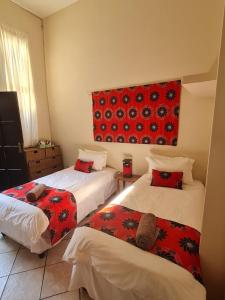 Habitación con 2 camas y una pared de color rojo. en Planet Scuba Bed and Breakfast, en Ponta do Ouro
