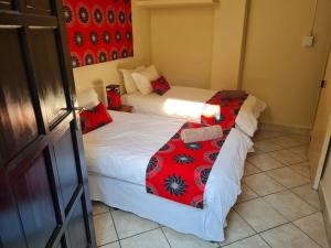 2 camas en una habitación pequeña con detalles en rojo en Planet Scuba Bed and Breakfast, en Ponta do Ouro