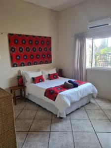 Schlafzimmer mit einem Bett mit einem roten Bild an der Wand in der Unterkunft Planet Scuba Bed and Breakfast in Ponta do Ouro