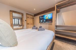 a bedroom with a large white bed and a tv at Luxury barn, newly renovated with river views in Staveley