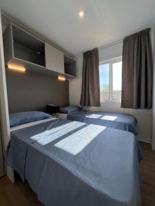 1 dormitorio con 2 camas y ventana en Mobile Homes Relax Park Umag, en Umag