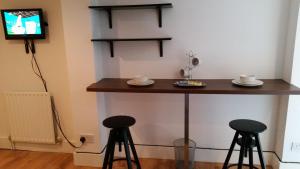 a bar in a room with two stools and a tv at Shepherd's Bush Flats in London