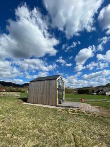 un pequeño edificio de madera en un campo con un cielo nublado en Domek pod Stromcem, en Czernica