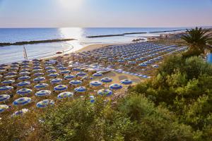 una spiaggia con ombrelloni blu e bianchi e l'oceano di Serena Majestic Hotel a Montesilvano