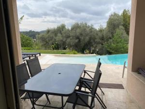 einen Tisch und Stühle auf einer Terrasse neben einem Pool in der Unterkunft Villa l'Olivier in Cagnes-sur-Mer