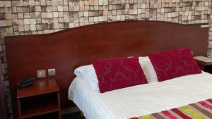 a bed with a red pillow and a wooden headboard at Hôtel Fontaine Morlaix in Morlaix