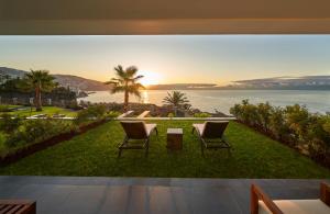 two chairs sitting on a lawn with a view of the ocean at Les Suites at The Cliff Bay - PortoBay in Funchal