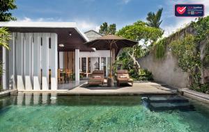 a pool with an umbrella next to a house at Villa Kayu Lama in Ubud