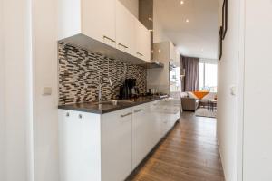 a kitchen with white cabinets and a brick wall at Biebosch in Bemelen