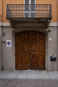 una gran puerta de madera en un edificio con balcón en ROMA PREMIUM by IDEA MONFERRATO sas, en Casale Monferrato