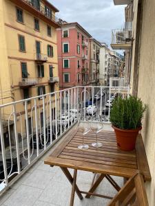 two wine glasses on a wooden table on a balcony at Colombo 32 Affittacamere in La Spezia