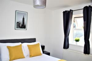 a bedroom with a bed with yellow pillows and a window at Contractor's Bliss- 5-Bedroom House with Free Parking for 7 Guests, Super Fast Wifi- Fran Properties! in Aylesbury