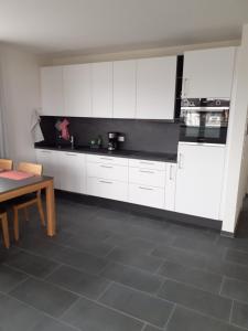 a kitchen with white cabinets and a table in it at Ferienwohnung Marek in Friedrichshafen