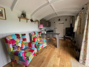 a living room with two chairs and a table at 'The Barrington' - Westwell Downs Shepherd Huts in Burford