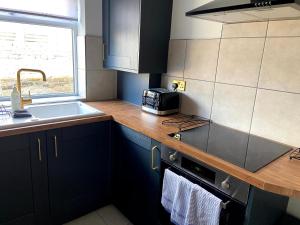 a kitchen with a sink and a stove top oven at The Seagull, with driveway and patio garden in Whitstable