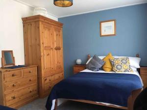 a blue bedroom with a bed and a wooden dresser at The Seagull, with driveway and patio garden in Whitstable