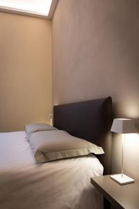 Un dormitorio con una cama y una mesa con una lámpara. en ROMA PREMIUM by IDEA MONFERRATO sas, en Casale Monferrato