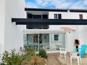 uma casa branca com um pátio com cadeiras azuis em Maison des loriots, charme marin, plage à 100m em Saint-Jean-de-Monts