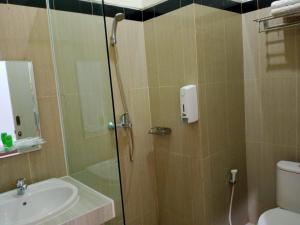 uma casa de banho com um chuveiro, um WC e um lavatório. em UNP Hotel & Convention em Padang