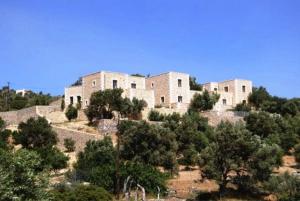 a large building on top of a hill with trees at Litiniana Villas in Triopetra