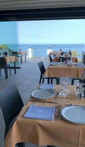 a restaurant with tables and chairs with a view of the ocean at Hotel L'Oasi in Cala Gonone