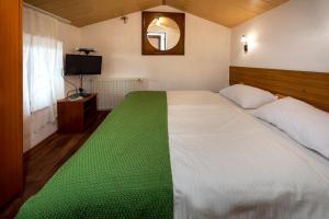 sypialnia z dużym białym łóżkiem i zielonym kocem w obiekcie Apartment Pod Lipom w mieście Roč