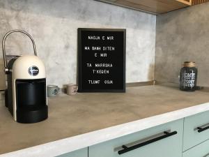 a kitchen counter with a sink and a sign on the wall at Diti's Apartment in Shkodër