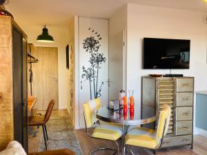 a dining room with a table with chairs and a tv at Studio neuf,vintage,terrasse,wifi ,excellence face mer in Saint-Hilaire-de-Riez