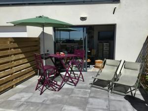 a purple table and chairs with an umbrella on a patio at Studio neuf déco vintage face mer,terrasse ,jardin,wifi,parking sous-sol in Saint-Hilaire-de-Riez
