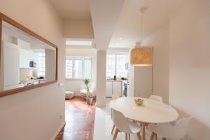 uma sala de jantar branca com uma mesa e cadeiras brancas em FLH Estefânia Charming Flat em Lisboa