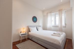um quarto branco com uma cama branca e uma janela em FLH Estefânia Charming Flat em Lisboa