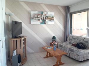 a living room with a couch and a table with a tv at Appartement charmant à Cagnes-sur-Mer - 38 m² - Piscine in Cagnes-sur-Mer