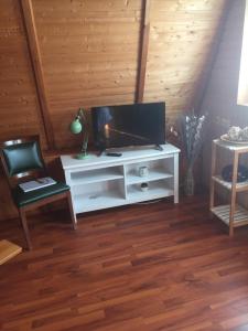 a living room with a tv on a white entertainment center at Ferienhaus Typ - Finnhütte in Mühl Rosin