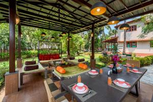 uma área de refeições exterior com mesas e cadeiras em Saffronstays Casa Del Palms, Alibaug - luxury pool villa with chic interiors, alfresco dining and island bar em Alibaug