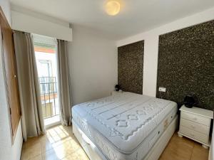 1 dormitorio con cama blanca y ventana grande en Rinconada Real Levante Beach, en Benidorm