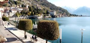 een uitzicht op een meer met mensen op een bankje bij My Holidays - La Terrazza sul Lago in Gravedona