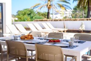 een witte tafel met eten op een patio bij Villa Sa Marinada | 100m de Mar in San Jose de sa Talaia