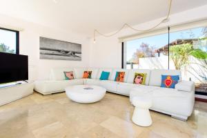 uma sala de estar com um sofá branco e uma televisão em Villa Sa Marinada | 100m de Mar em San Jose de sa Talaia