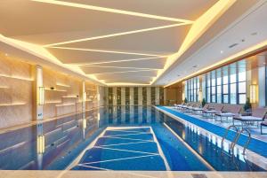 a swimming pool with chairs and tables in a building at Wyndham Jingzhou in Jingzhou