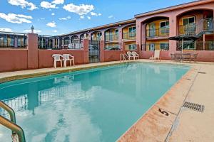 una piscina en un hotel con sillas y un edificio en Rodeway Inn Albuquerque Downtown on Rt 66 en Albuquerque