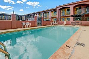 a swimming pool at a hotel with chairs and a building at Rodeway Inn Albuquerque Downtown on Rt 66 in Albuquerque